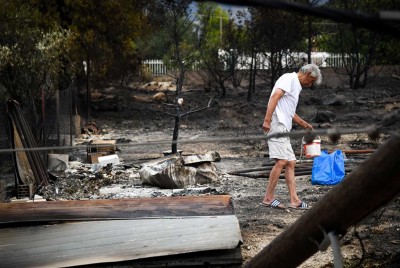 άνθρωπος κρατάει ένα κουβά μέσα σε καμμένο τοπίο