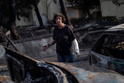 ηλικιωμένη γυναίκα μπροστά από καμένα αυτοκίνητα