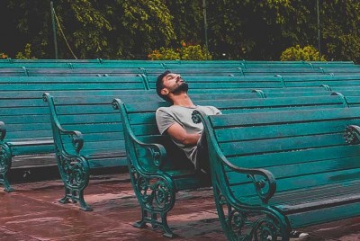 νέος άνδρας κάθεται σε παγκάκι και είναι μοναχικός και επιφυλακτικός