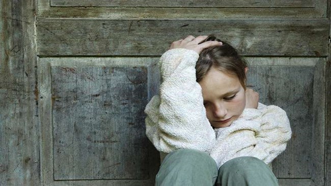 λυπημένη γυναίκα κάθεται κάτω με την πλάτη της σε μια πόρτα